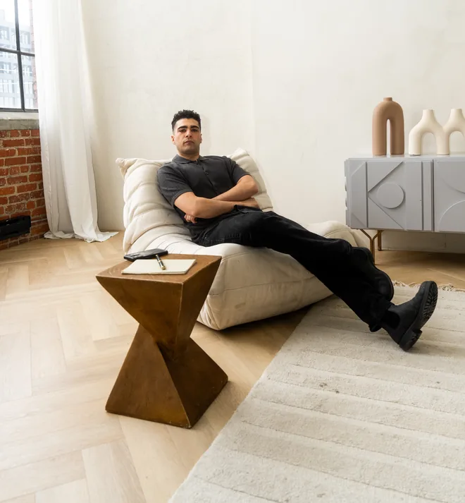 Kal Ayyoub seated in a downtown Toronto loft, with a steel window, exposed brick and herringbone floors